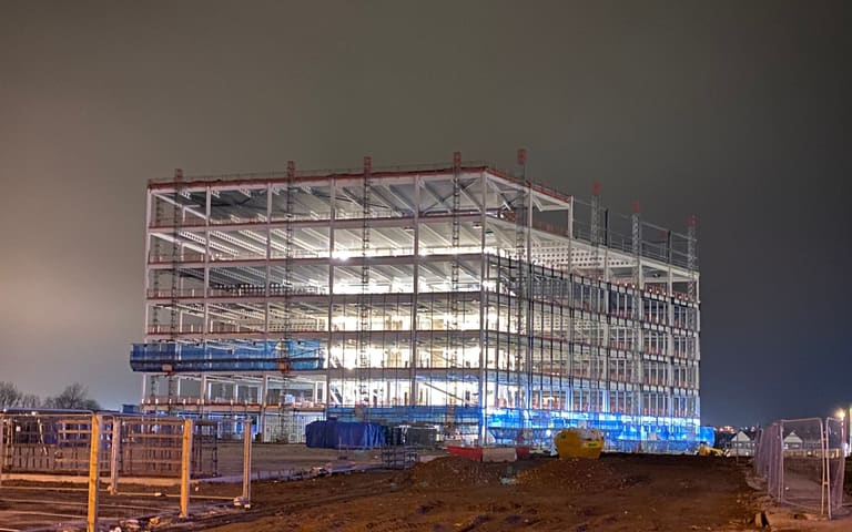 Steel frame rising on a cleared site, illustrative